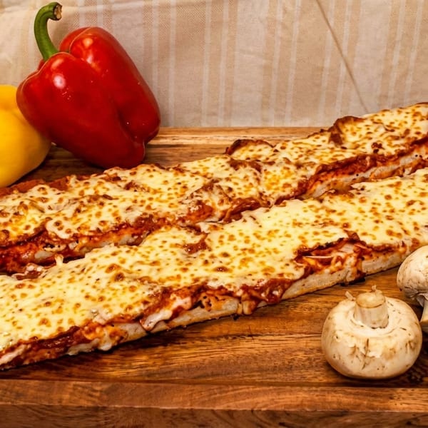 Two cheesy breadsticks with red and yellow bell peppers and mushrooms on a wooden board.