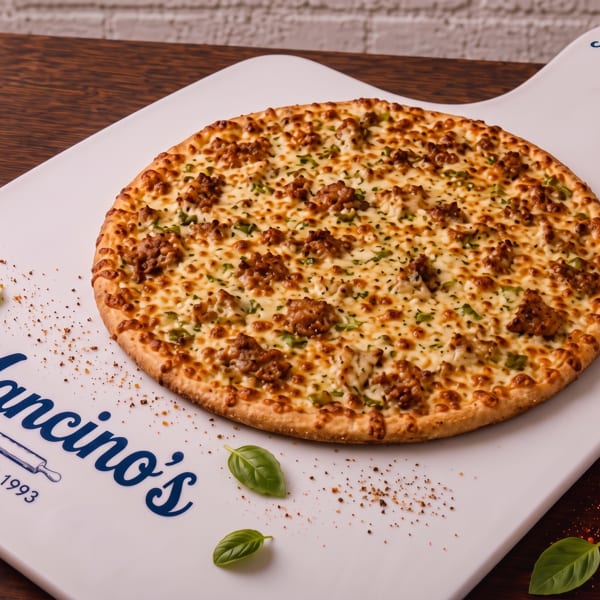 Cheesy sausage pizza garnished with herbs and basil on a Mancino’s branded serving board.