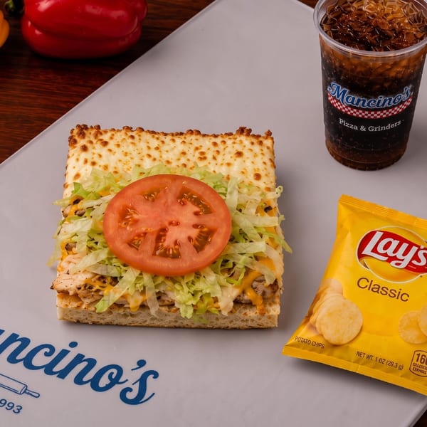A grilled chicken sub combo with chips and a Mancino's drink.